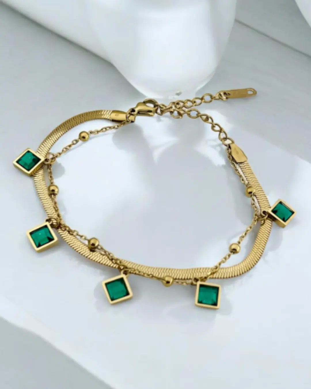 gold-plated bracelet featuring emerald-green charms